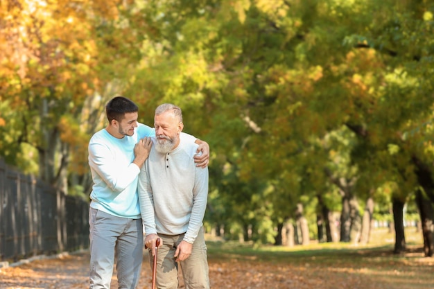 Joven cuidador caminando con un anciano en el parque