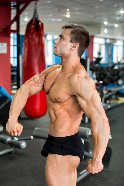 Joven culturista posando en el gimnasio