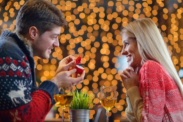 El joven le da un anillo de bodas a una chica en el restaurante