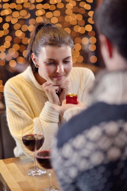 El joven le da un anillo de bodas a una chica en el restaurante