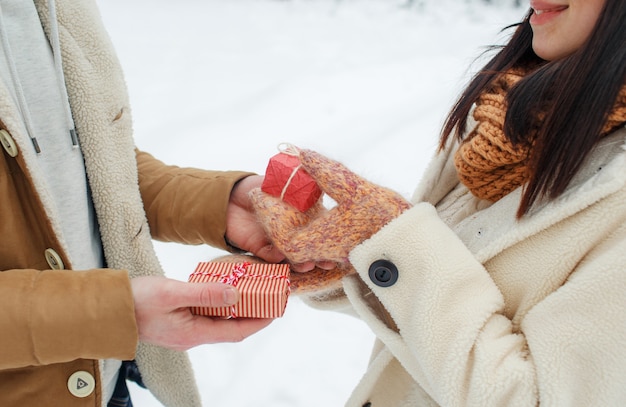 Un joven le da un regalo a una niña en un bosque nevado. Sorpresa para San Valentín.