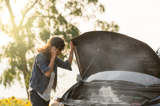 Foto una joven dama con un auto negro que se averió en el camino. quiero ayuda con el auto roto.