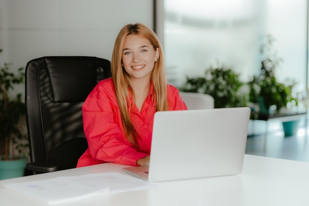 Joven dama sonriente con una computadora empleado feliz en el escritorio