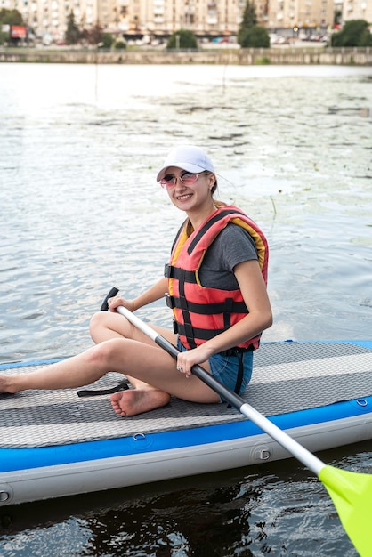 Una joven delgada monta una tabla de SUP en el lago de la ciudad