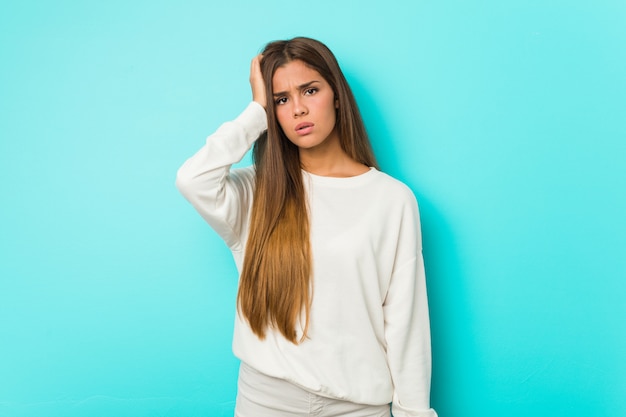 Joven delgada mujer cansada y con mucho sueño manteniendo la mano en la cabeza.