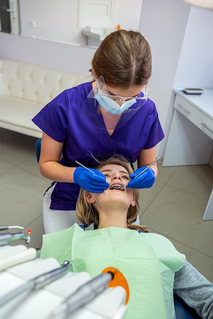 Una joven dentista comienza el tratamiento de todos los dientes enfermos de su cliente habitual