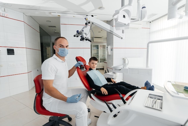 Un joven dentista examina y trata los dientes de un niño de ocho años en un primer plano moderno de odontología blanca Tratamiento de prótesis dentales y blanqueamiento dental Odontología moderna Prevención