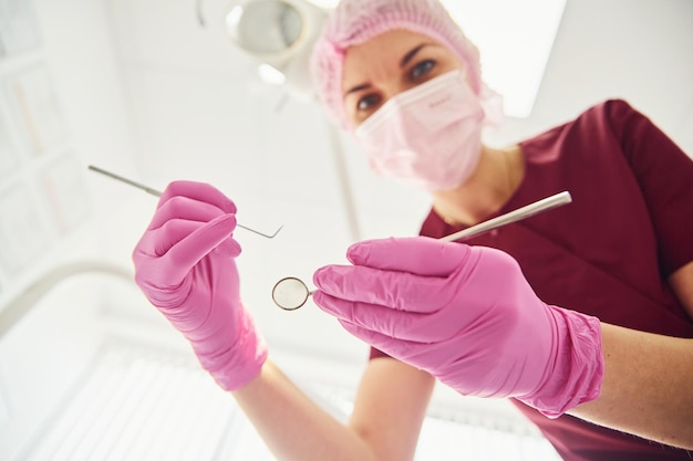 Joven dentista con máscara protectora que trabaja en la clínica de estomatología Vista en primera persona