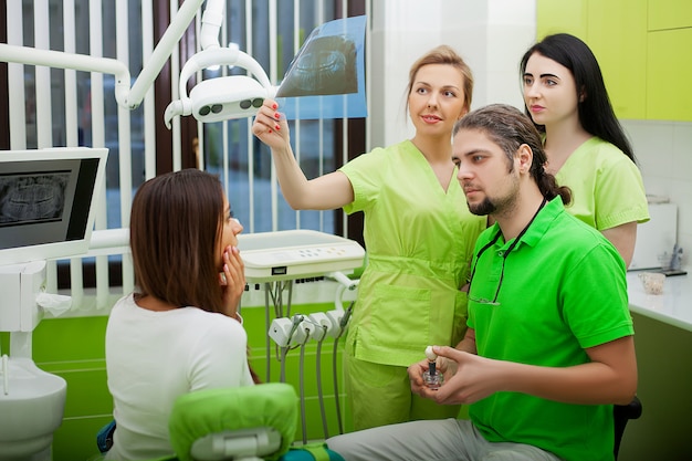 Joven dentista que trata a una paciente en el estudio dental