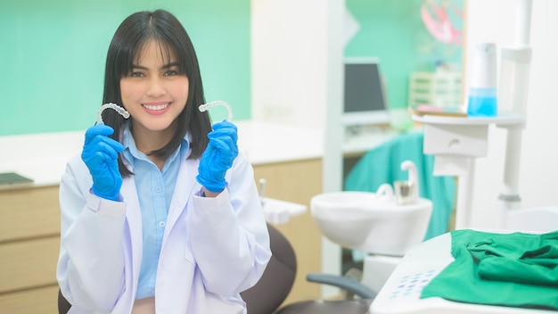 Una joven dentista sosteniendo invisalign en un chequeo de dientes de una clínica dental y un concepto de dientes sanos