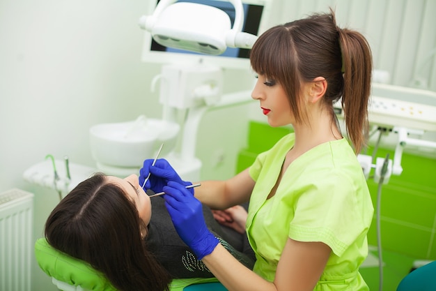 Joven dentista tratando a una paciente en el estudio dental