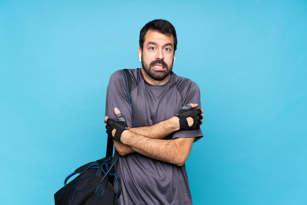 Joven deporte con barba sobre congelación de pared azul aislado