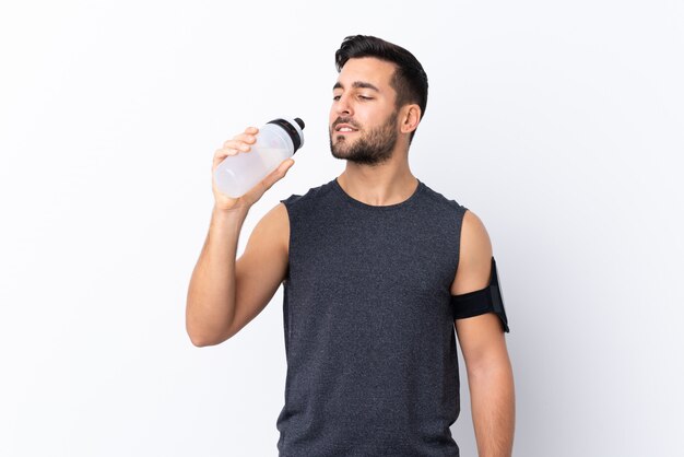 Joven deporte guapo con barba sobre blanco con botella de agua deportiva