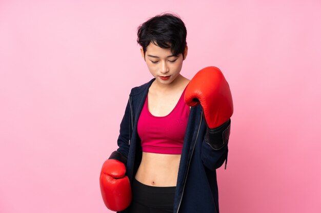 Joven deporte mujer asiática sobre pared rosa aislado con guantes de boxeo