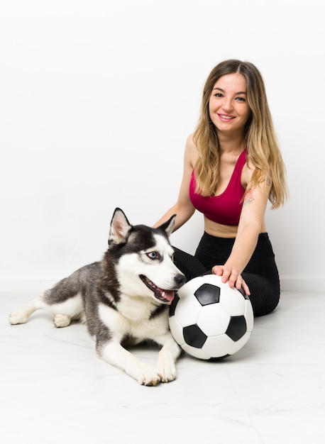 Joven deporte niña con su perro sentado en el suelo