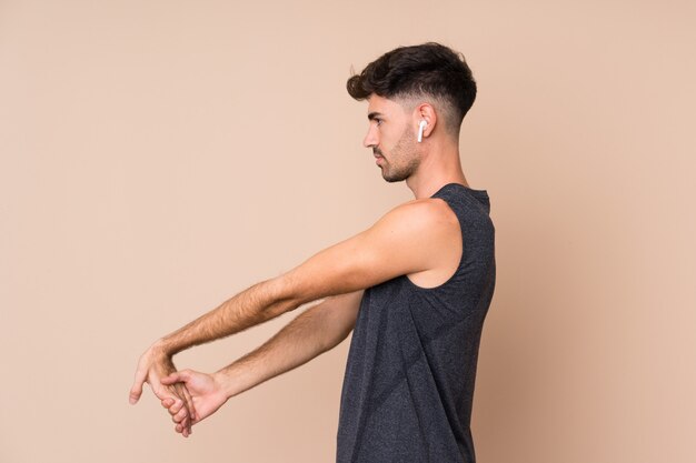 Foto joven deporte sobre fondo aislado estirando el brazo