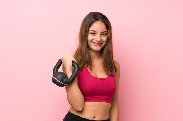 Joven deporte sobre rosa aislado haciendo pesas con pesas rusas