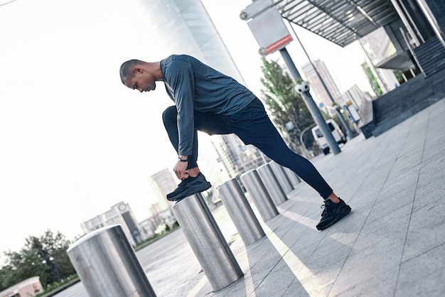 Joven de deportes urbanos está haciendo calentamiento antes de correr en la ciudad en un