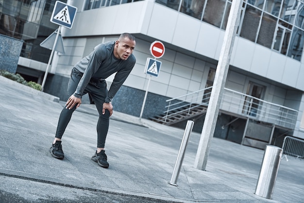 Joven de deportes urbanos está haciendo calentamiento antes de correr en la ciudad en un