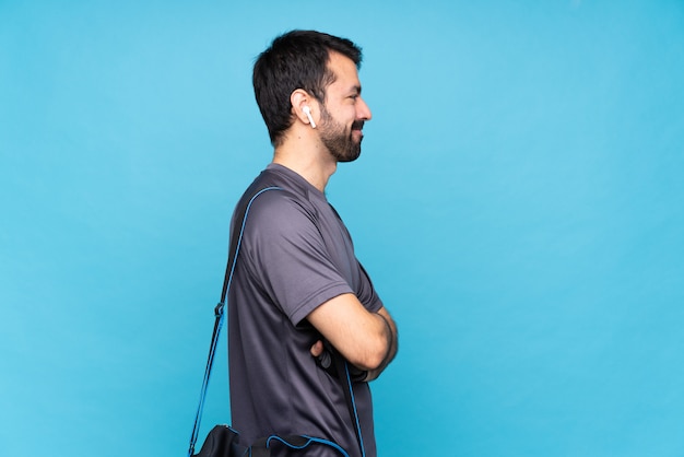 Foto joven deportista con barba sobre fondo azul aislado en posición lateral