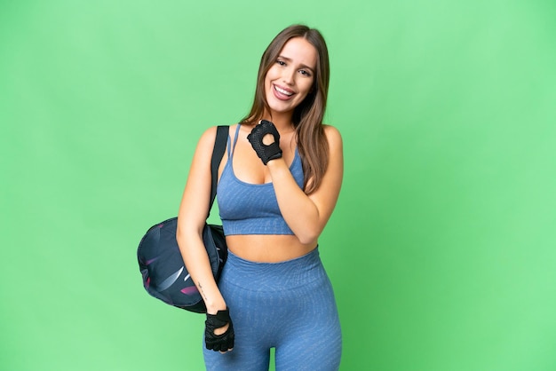 Joven deportista con bolsa deportiva sobre un fondo aislado de clave de croma celebrando una victoria