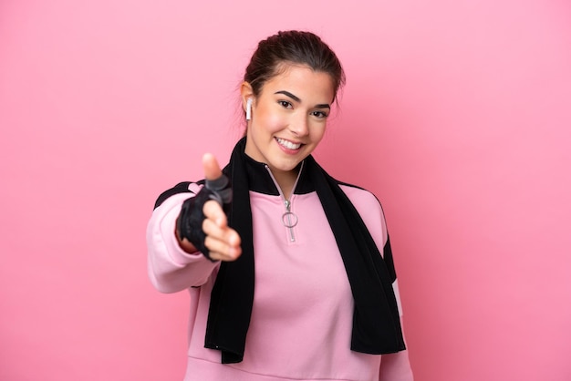 Joven deportista brasileña aislada de fondo rosa dándose la mano por cerrar un buen trato