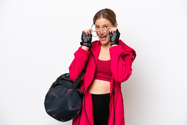 Joven deportista caucásica aislada de fondo blanco con gafas y sorprendida