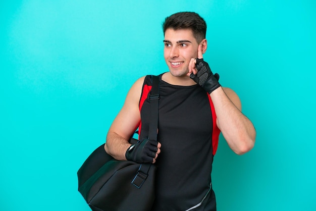 Joven deportista caucásico con bolsa deportiva aislada de fondo azul pensando en una idea mientras mira hacia arriba