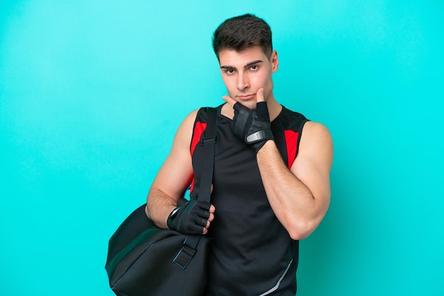 Joven deportista caucásico con bolsa deportiva aislada en el pensamiento de fondo azul