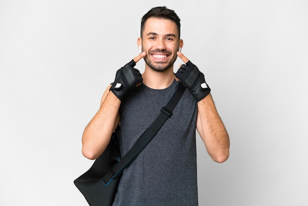 Joven deportista caucásico con bolsa deportiva sobre un fondo blanco aislado sonriendo con una expresión feliz y agradable