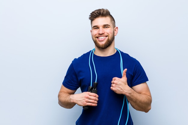 Joven deportista caucásico con una cuerda de saltar sonriendo y levantando el pulgar