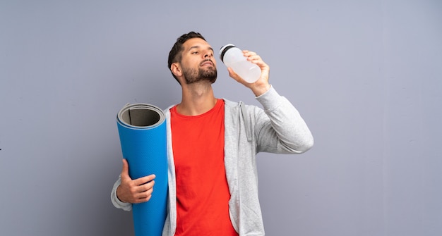 Joven deportista con colchoneta y una botella de agua