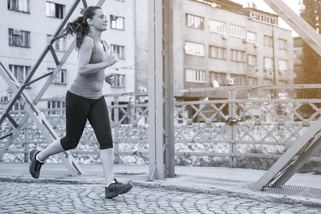 joven deportista corriendo por el puente en la mañana soleada en la ciudad