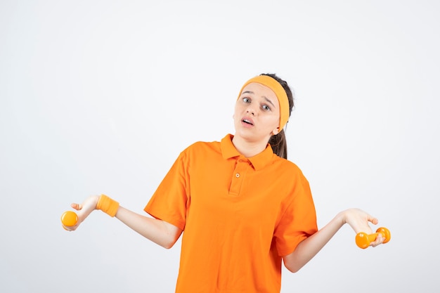 joven deportista en entrenamiento de camiseta naranja con pesas.