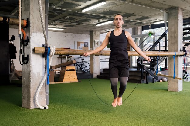 Joven deportista entrenando saltando la cuerda en el gimnasio