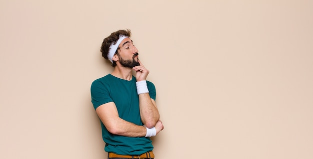 Joven deportista expresando un concepto contra la pared plana