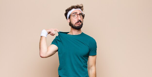 Joven deportista expresando un concepto contra la pared plana