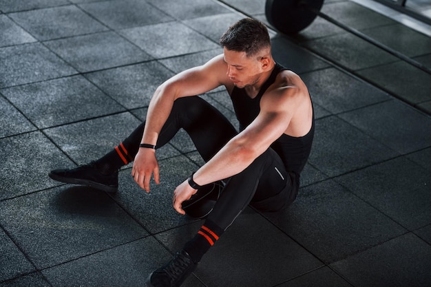 Joven deportista fuerte vestido de negro tiene un día de entrenamiento en el gimnasio