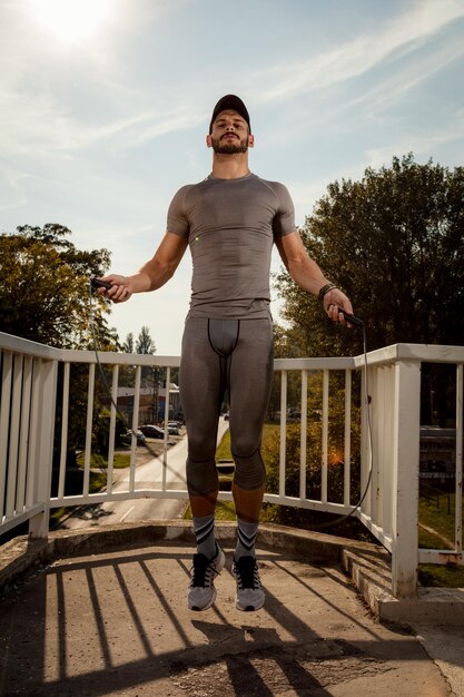 Joven deportista haciendo ejercicio en el puente. Mirando a la cámara.