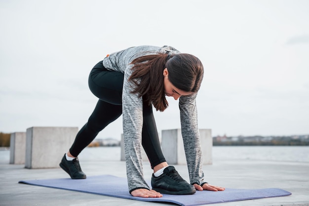 cargando moneda Dedicación Joven deportista haciendo ejercicios de yoga en la alfombra de fitness al  aire libre cerca del lago durante el día | Foto Premium