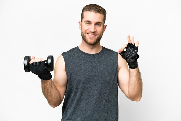Joven deportista haciendo levantamiento de pesas sobre fondo blanco aislado que muestra el signo de ok con los dedos