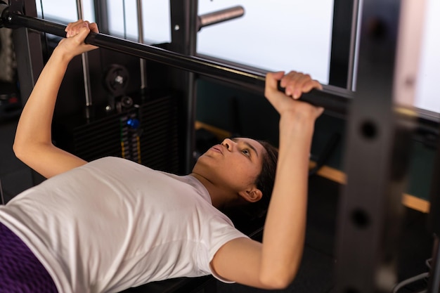 Foto joven deportista hispana levantando pesas en el gimnasio