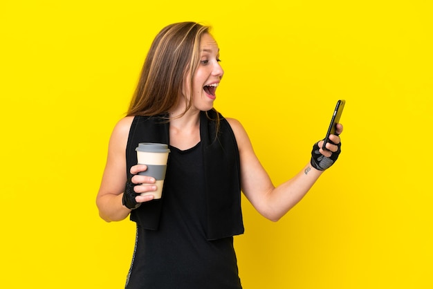 Joven deportista inglesa aislada de fondo blanco sosteniendo café para llevar y un móvil