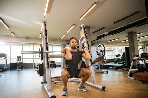 Joven deportista levantando una barra en el gimnasio