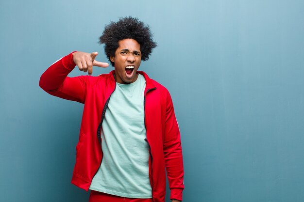 Joven deportista negro apuntando a la cámara con una expresión agresiva enojada que parece un jefe furioso y loco en la pared del grunge