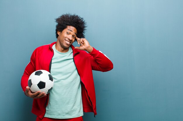 Joven deportista negro con un balón de fútbol azul grunge wa