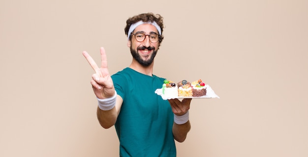 Joven deportista con pasteles contra la pared plana