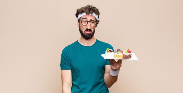 Joven deportista con pasteles en pared plana