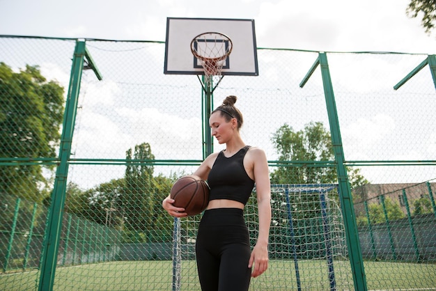 Joven deportista con una pelota de baloncesto en la cancha de baloncesto al aire libre fin de semana activo