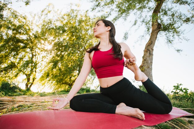 Joven deportista practicando yoga al aire libre a orillas del lago